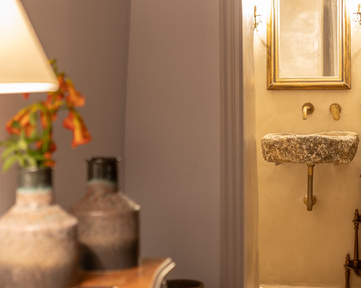 The private bathroom at Casa di Lavalle, with a sink carved from natural Tinos stone and brushed brass fixtures.
