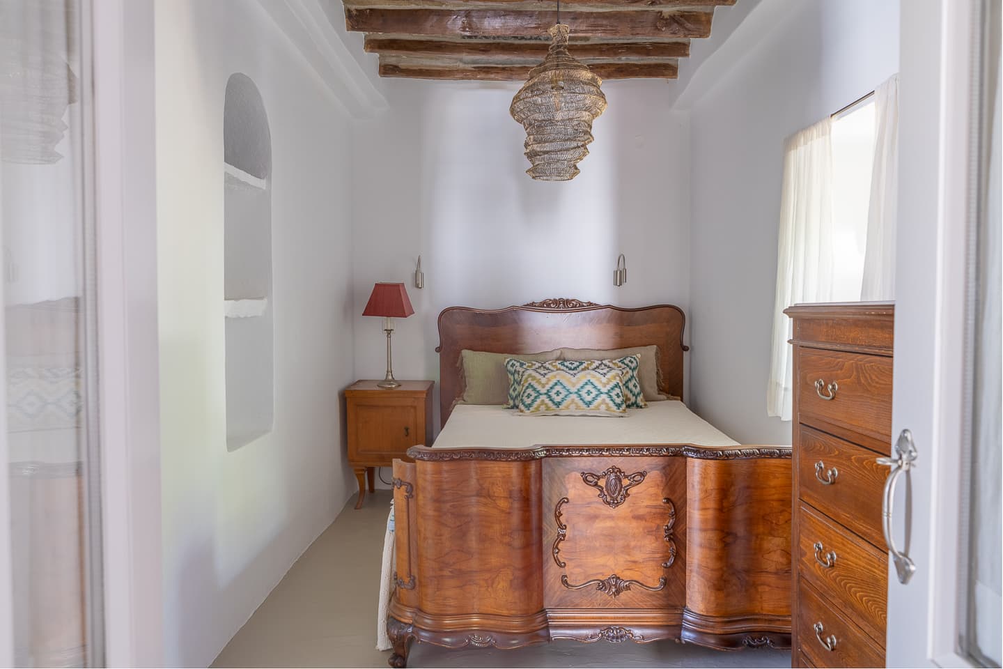 The double bedroom at Casa di Lavalle, with a carved antique wooden bed frame beneath an exposed timber ceiling.