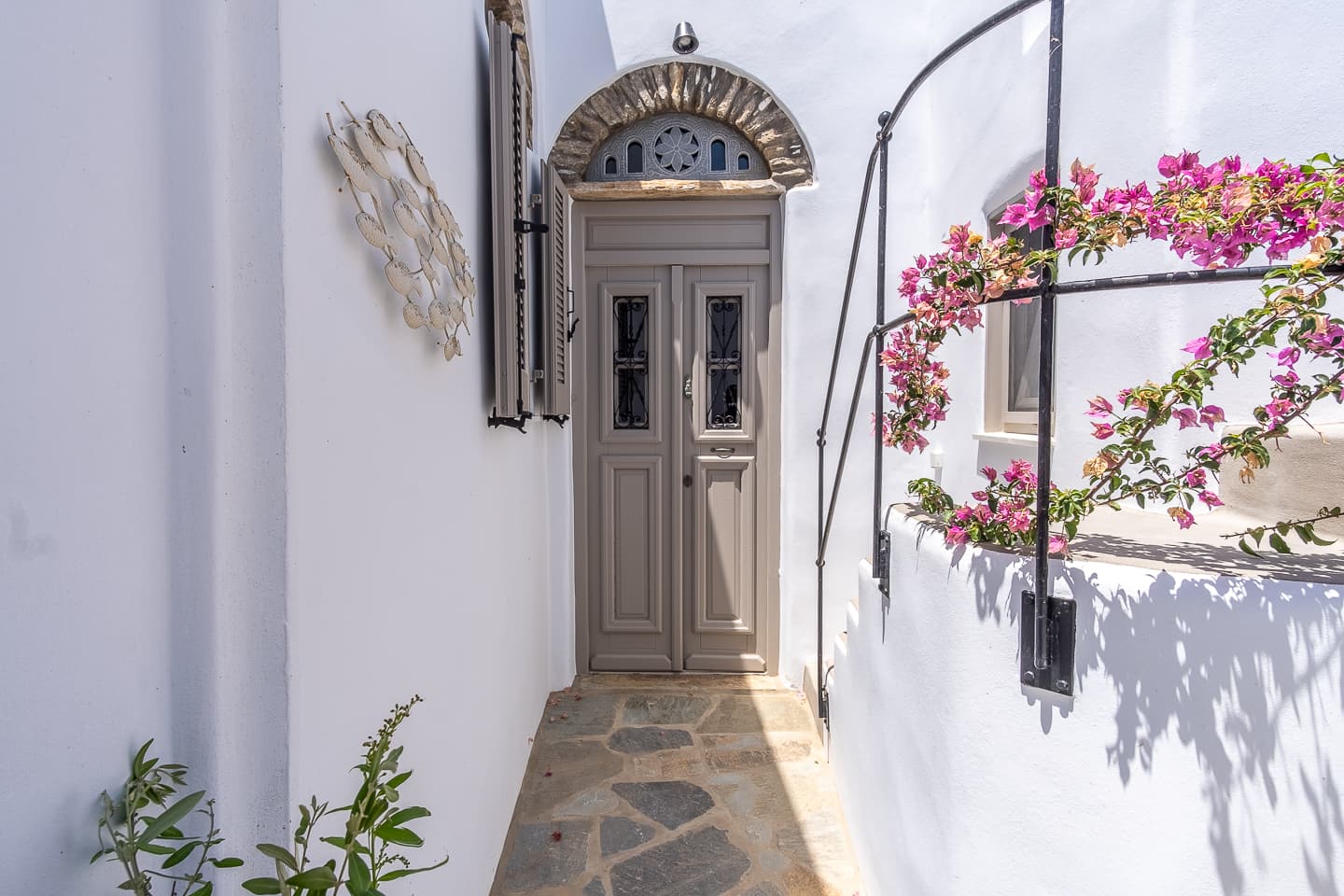 The arched front door of Casa di Lavalle at the end of a narrow whitewashed passage, bougainvillea climbing beside it.